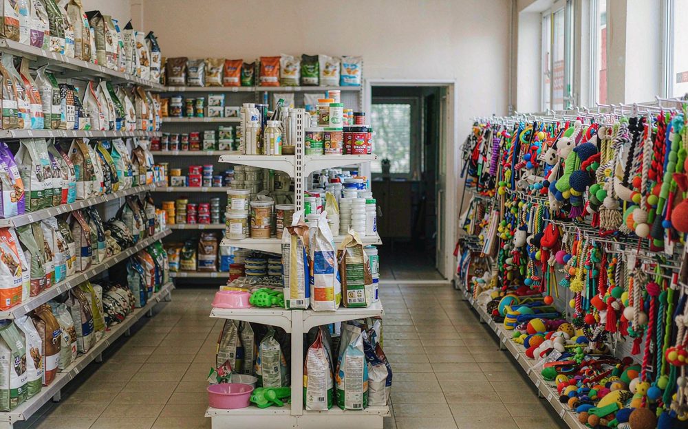 Shelves of pet food bags and pet toys in a pet store aisle